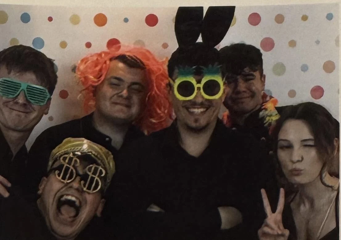 Wspólne zdjęcie kobiety i mężczyzn w kolorowych przebraniach z fotobudki.